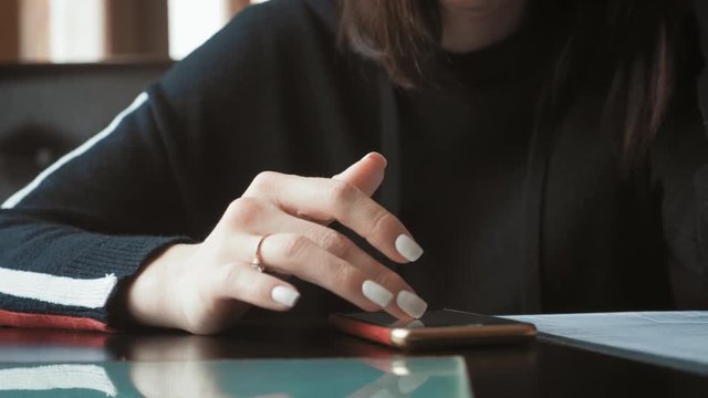 Young wonam use mobile phone while sitting in comfortable coffee shop during work break, charming happy female reading fashion news on cell telephone during breakfast in restaurant.