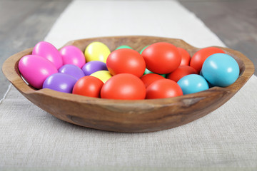 Obraz na płótnie Canvas Multicoloured Easter eggs in a large wooden bowl