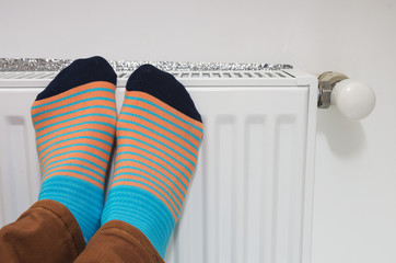 Female feet in bright socks against the background of a house heater. Conceptual image of home...