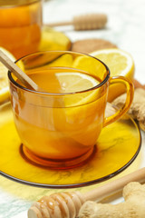 A yellow cup of tea, with ginger roots, lemon and spices. A healthy lifestyle, anti-flu and anti-inflammatory concept.