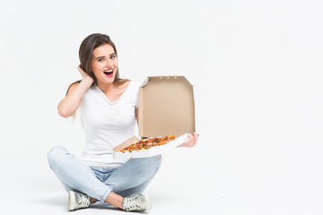 Beautiful blonde hungry woman in white casual shirt sitting on floor and eating pieces of hot tasty pizza. Healthy and junk food concept. Diet. Calories Copy space.