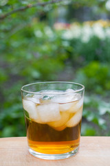 Glass of ice tea on wooden with nature background -