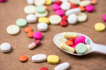 pills in white spoon with wood background