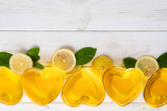 Yellow lemon jelly in heart shaped glass wish slices of lemon and green leafs  on white wooden background, top view