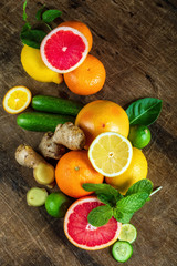 Raw fruit whole and cut on wooden background, as a lemon, grapefruit, orange, mint, cucumber and ginger