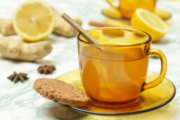 A yellow cup of tea, with ginger roots, lemon and spices. A healthy lifestyle, anti-flu and anti-inflammatory concept.