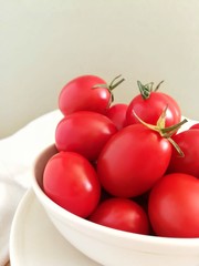 Fresh cherry tomatoes in a bowl on a light background close-up . With selectiv focus. 