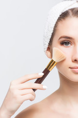 Gorgeous woman with natural make-up holding a brush on face!