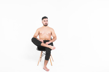 Fototapeta premium Suntanned male model relaxing on a chair in a white background!