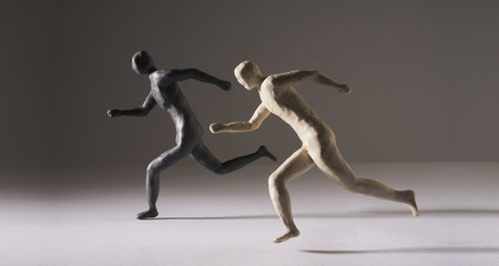 Black and white men run in the same direction. Studio Shot. With space copy text. Isolated on dark background.