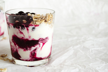 Ice cream with berries and muesli. Ice cream in a glass with currants, berry jam and muesli on a white background. Close-up. Free space for text