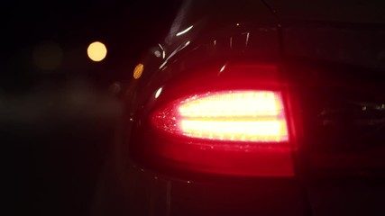 Car detail. New led taillight shining red at night. The rear lights of the car, in hybrid sports car. Developed car's rear brake light. Close up view