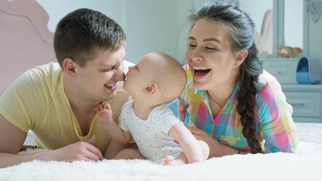 Happy family - mother, father and baby on the bed
