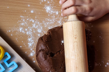 Hands of little girl sheeting dough with rolling pin. Cooking traditional Easter biscuits. Easter...