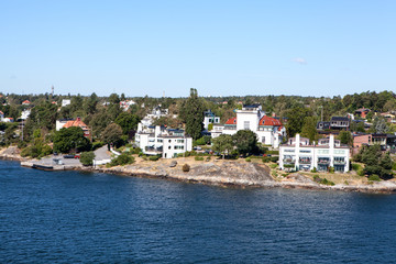 Fototapeta na wymiar Many different building and houses are on coastline of Stockholm archipelago in Sweden. Joint valley landscape. Scandinavia