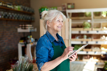 Shop assistant with digital tablet in small grocery store
