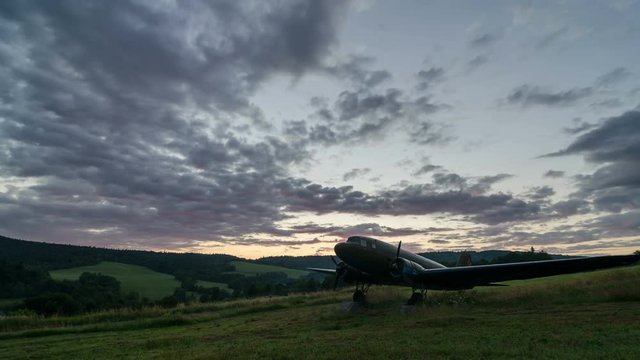 Colorful clouds sunset sky over old military aircraft in green nature landscape Time lapse