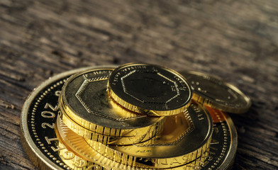 A few gold coins fineness 999.9 on a background of blurred wood texture.