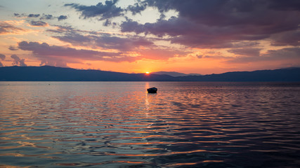 Sunset over Ohrid's lake, North Macedonia, Europe, with boat and cloudy sky