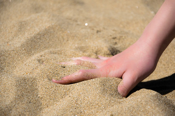 Hand in the soft sand of the sea