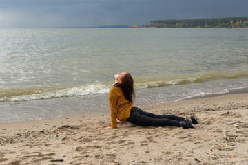 Fototapeta na wymiar Woman practicing yoga against the blue sky and the azure sea on the sandy shore.