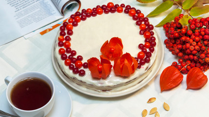 Homemade cake decorated with red physalis berries and flowers called 
