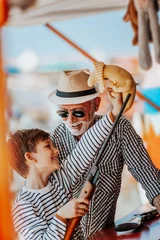 Foto auf Leinwand Großvater und Enkel haben Spaß und verbringen gute Zeit zusammen im Vergnügungspark. Kind schießt mit Luftgewehr, während Opa ihm hilft, den Preis zu gewinnen. © Dusko