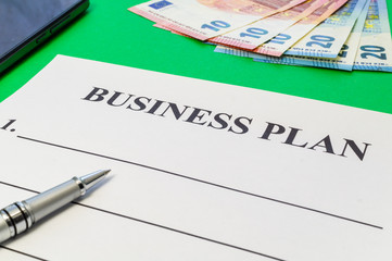 A business plan template to fill out with pen, money and smartphone.