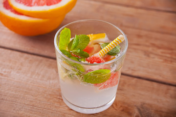 Lemonade or mojito cocktail with grapefruit and mint, cold refreshing drink or beverage on the wooden background.