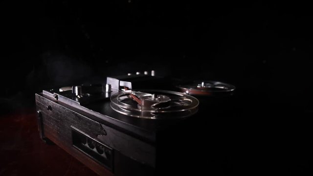 Old vintage reel to reel player and recorder on dark toned foggy background. Analog Stereo Open Reel Tape Deck Recorder Player with Reels. Selective focus