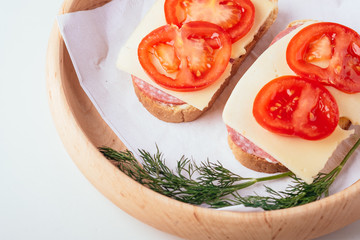 Quick cooking sandwiches with ham meat cheese tomato dill on wooden plate