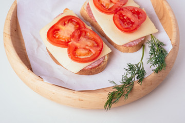 Quick cooking sandwiches with ham meat cheese tomato dill on wooden plate