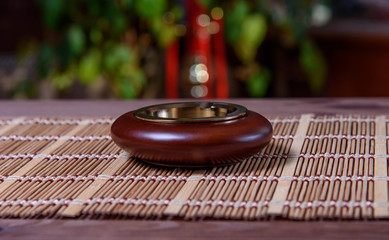 Stylish exquisite ashtray on the table. Ashtray on a bamboo napkin.