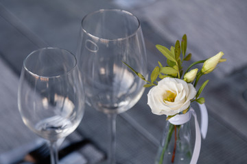 Modern restaurant setting, glass vase with bouquet flowers on table in restaurant. Wine and water glasses stand on wooden table. Concept banquet, birthday, conference, wedding