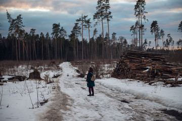 Winter landscape with road and clouds. The girl goes away at sunset