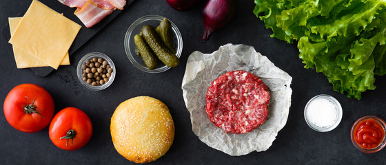 Top view of raw ingredients for the homemade burger on black cocnrete background.