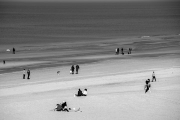 Fototapeta na wymiar People are walking on the sandy beach at spring at Scheveningen Strand - Den Haag