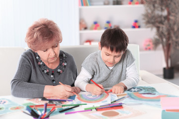 grandmother and grandson paint a rainbow in the nursery