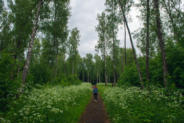 Girl on the road in the forest among the flowers