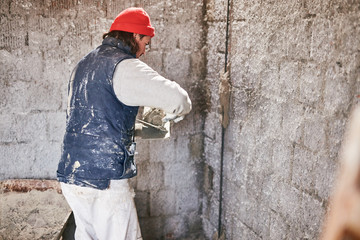 Real construction worker making a wall inside the new house.