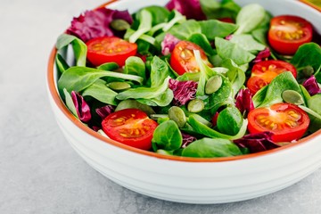 Fresh green salad bowl with radicchio, tomatoes and pumpkin seeds.