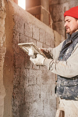 Real construction worker making a wall inside the new house.