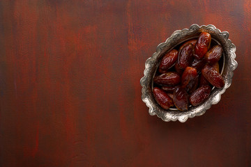 Bowl of dates on a painted  red brown wooden table. Top view