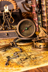 Fototapeta na wymiar Antique compass on the background of a treasure chest with gold and books. Vintage style. 1565 old map of the year.