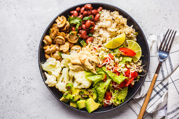 Vegetarian lunch. Brown rice with mushrooms, beans, salad and hummus in black plate, clean eatind.