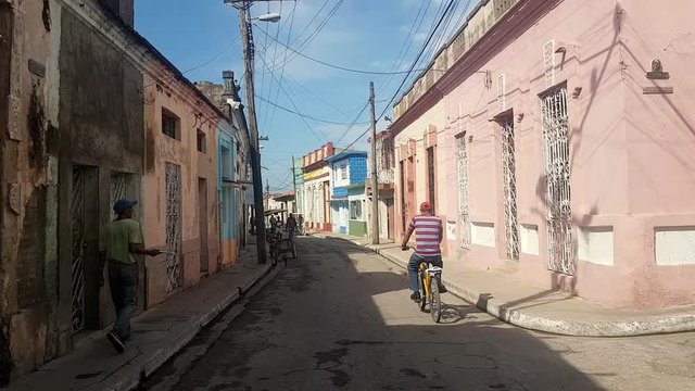 Cuban man driving bike in the colorful street in the city of Havana