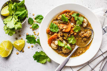 Lentil soup with vegetables in a white plate, white background, top view. Plant based food, clean eating.