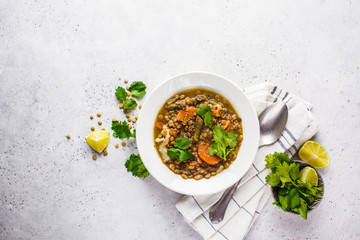 Lentil soup with vegetables in a white plate, white background, top view. Plant based food, clean...