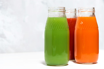 colorful vegetable juices in bottles on white background, closeup