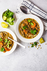 Lentil soup with vegetables in a white plate, white background, vertical. Plant based food, clean...